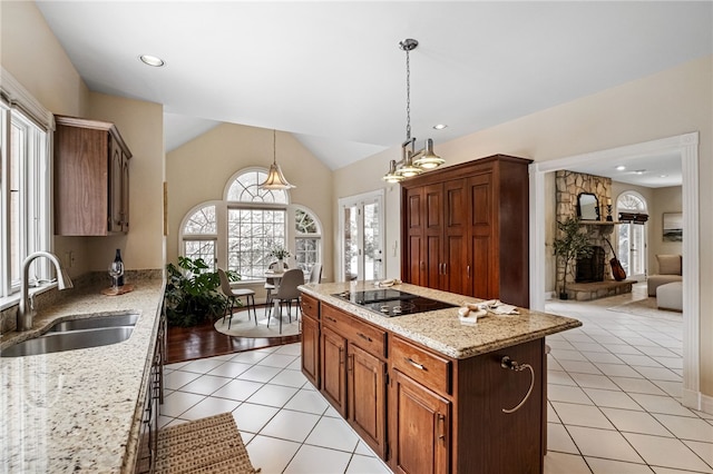 kitchen with sink, a center island, pendant lighting, vaulted ceiling, and black electric stovetop