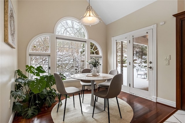 dining room with a wealth of natural light, wood-type flooring, and lofted ceiling