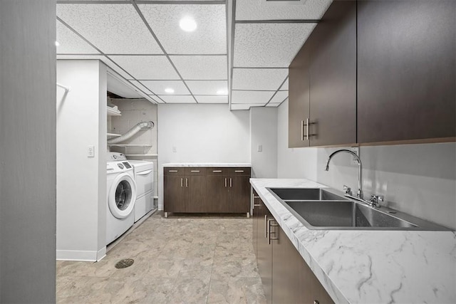 kitchen with washer and clothes dryer, a drop ceiling, dark brown cabinetry, and sink