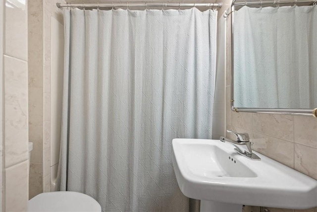 bathroom with decorative backsplash, toilet, and sink