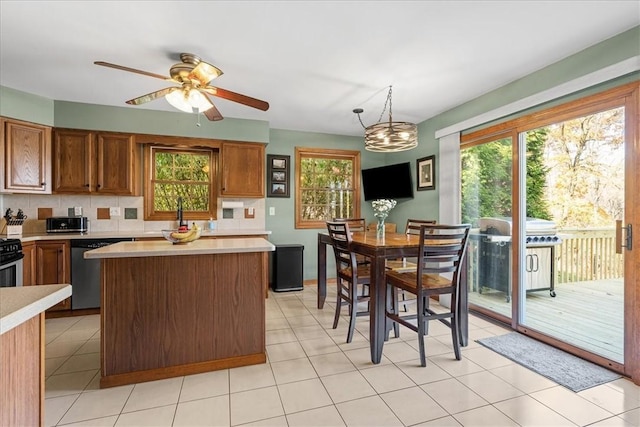 kitchen with tasteful backsplash, ceiling fan with notable chandelier, decorative light fixtures, dishwasher, and a kitchen island