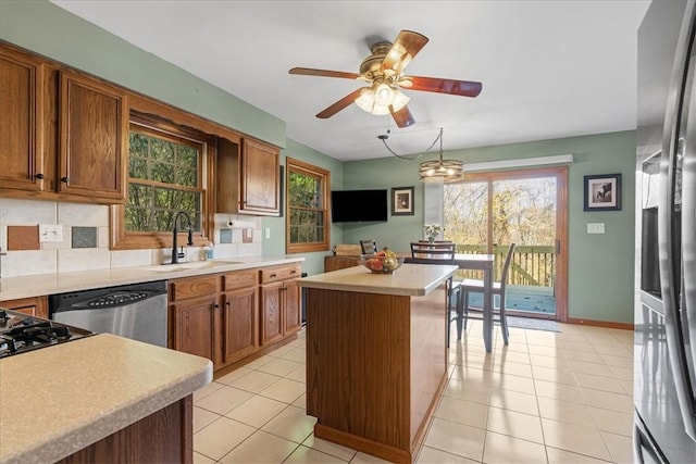 kitchen featuring a center island, sink, light tile patterned floors, appliances with stainless steel finishes, and decorative light fixtures