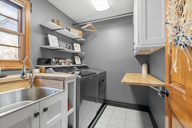 laundry area featuring washer and dryer, sink, light tile patterned floors, and cabinets