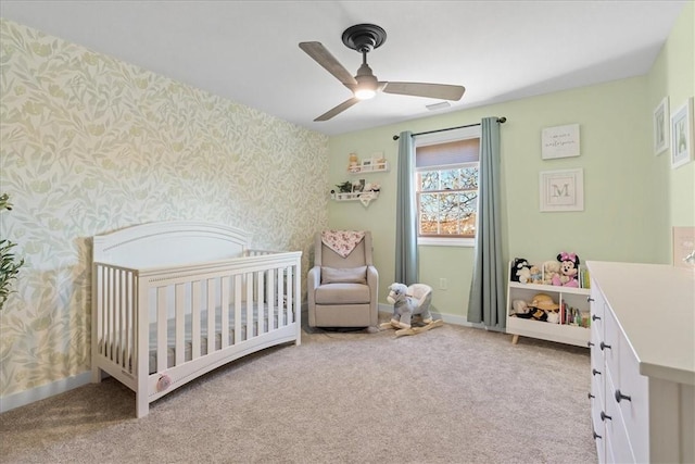 carpeted bedroom with ceiling fan and a crib