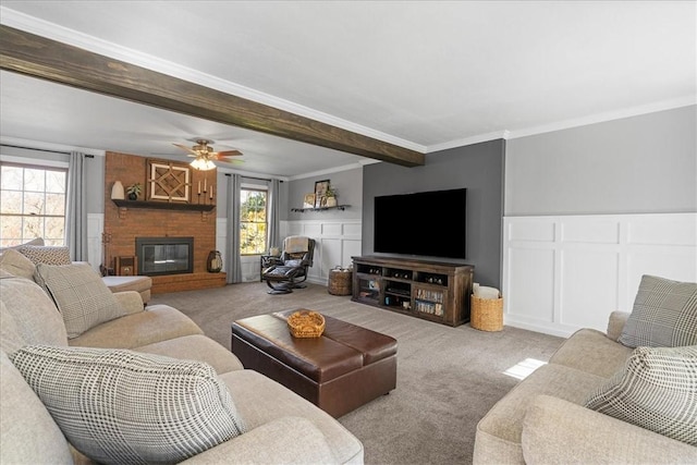 carpeted living room with a brick fireplace, ceiling fan, and ornamental molding