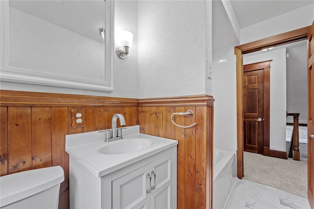 bathroom with a washtub, vanity, and toilet