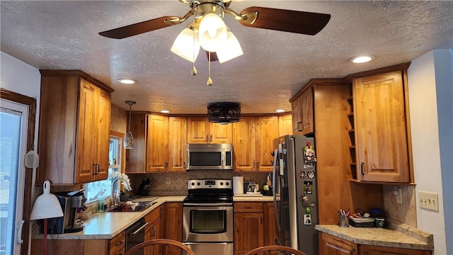 kitchen featuring ceiling fan, sink, stainless steel appliances, backsplash, and a textured ceiling