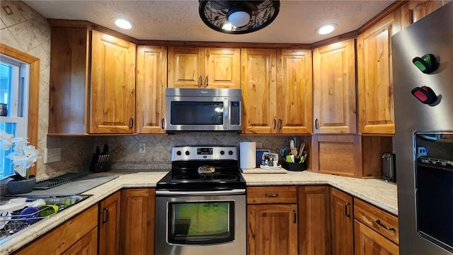 kitchen with tasteful backsplash, a textured ceiling, and appliances with stainless steel finishes