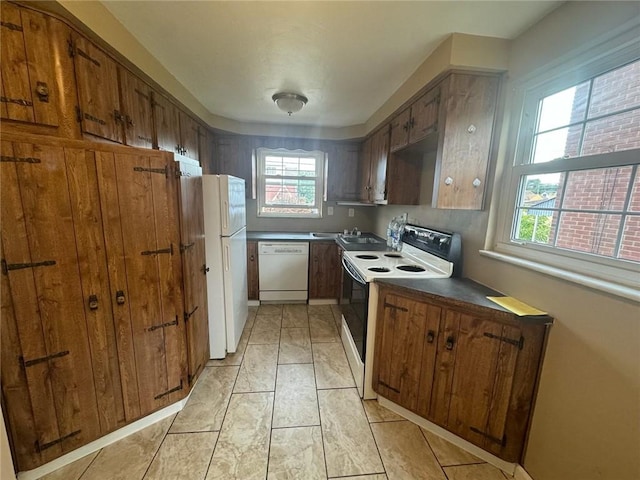 kitchen featuring light tile patterned floors, white appliances, a healthy amount of sunlight, and sink