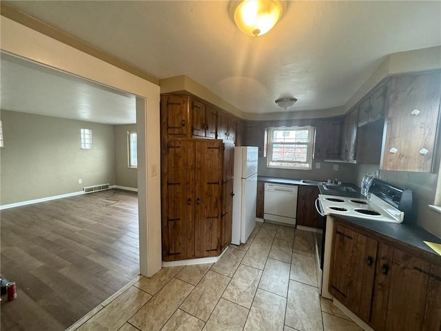 kitchen featuring a healthy amount of sunlight, dark brown cabinetry, and white appliances