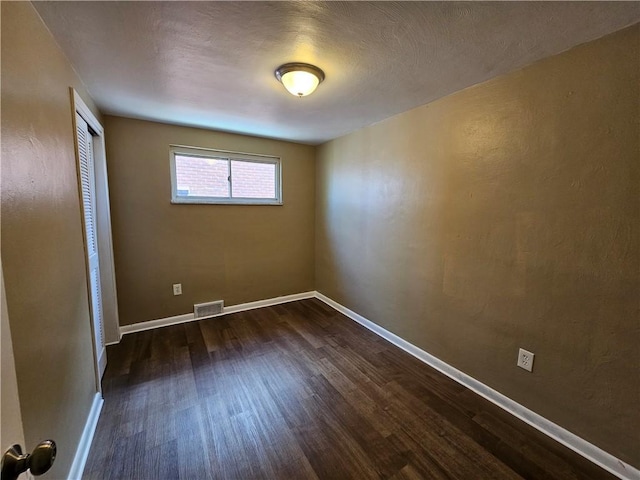 empty room with a textured ceiling and dark wood-type flooring