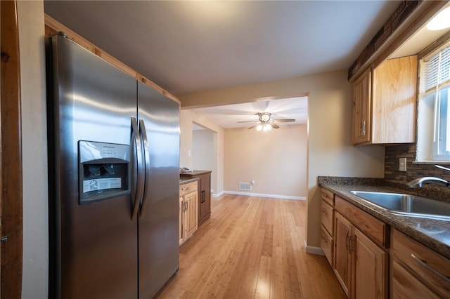 kitchen featuring stainless steel fridge, ceiling fan, backsplash, light hardwood / wood-style flooring, and sink