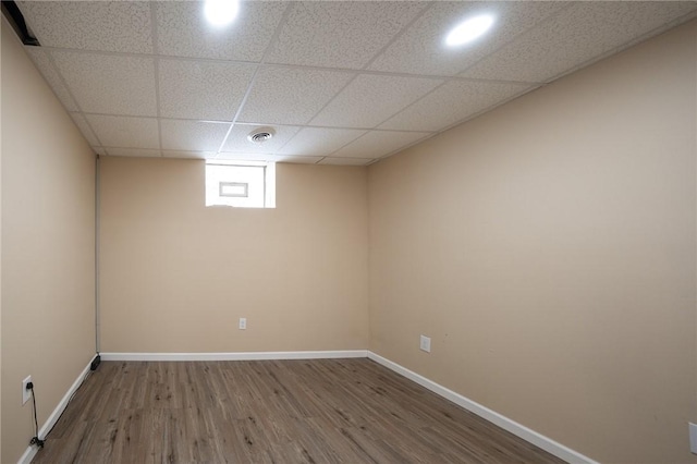 unfurnished room with a paneled ceiling and wood-type flooring