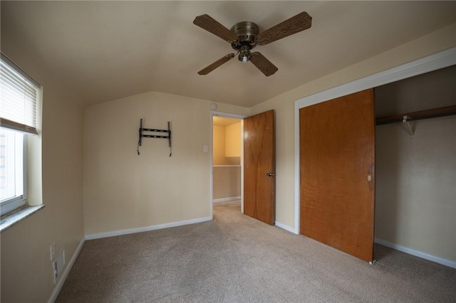 unfurnished bedroom featuring ceiling fan, light carpet, a closet, and lofted ceiling