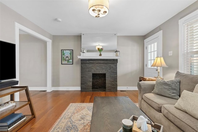 living room featuring a stone fireplace and hardwood / wood-style flooring