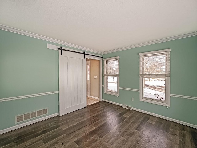 unfurnished bedroom featuring a barn door, dark hardwood / wood-style flooring, and ornamental molding