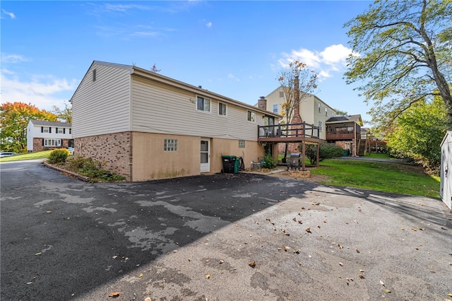 back of property with a deck and a lawn