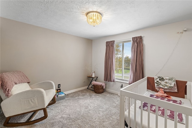 carpeted bedroom with a textured ceiling and a nursery area