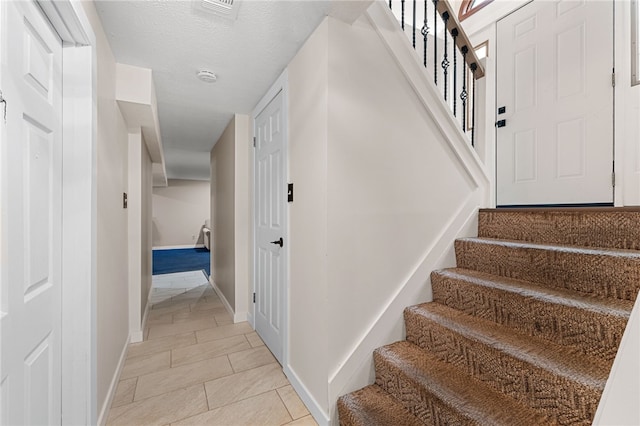 stairway featuring a textured ceiling and tile patterned floors