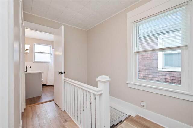 hall with light hardwood / wood-style floors, ornamental molding, and sink