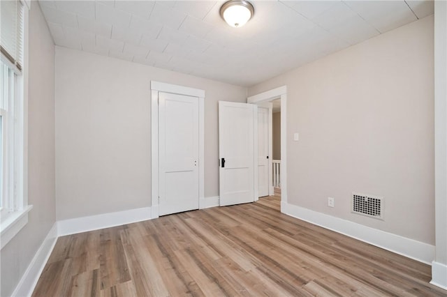 unfurnished bedroom featuring light wood finished floors, visible vents, a closet, and baseboards