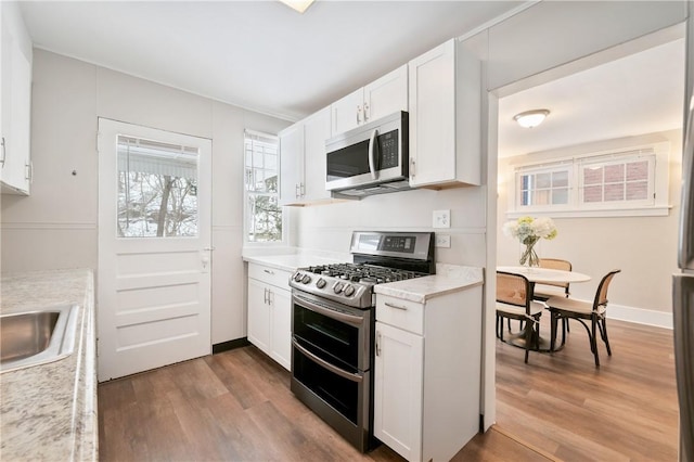 kitchen featuring wood-type flooring, sink, white cabinetry, and stainless steel appliances