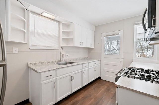 kitchen with sink, dark hardwood / wood-style flooring, gas stove, light stone counters, and white cabinetry