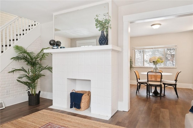 living room with visible vents, wood finished floors, brick wall, baseboards, and stairs