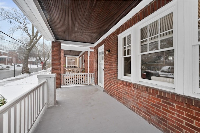 snow covered back of property featuring a porch