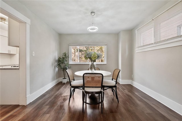 dining space featuring dark wood-type flooring and baseboards