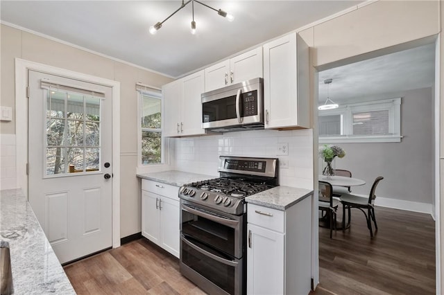 kitchen with backsplash, dark wood-type flooring, light stone counters, appliances with stainless steel finishes, and white cabinets