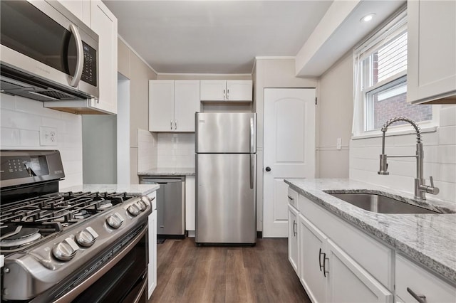 kitchen with tasteful backsplash, a sink, appliances with stainless steel finishes, white cabinetry, and dark wood-style flooring