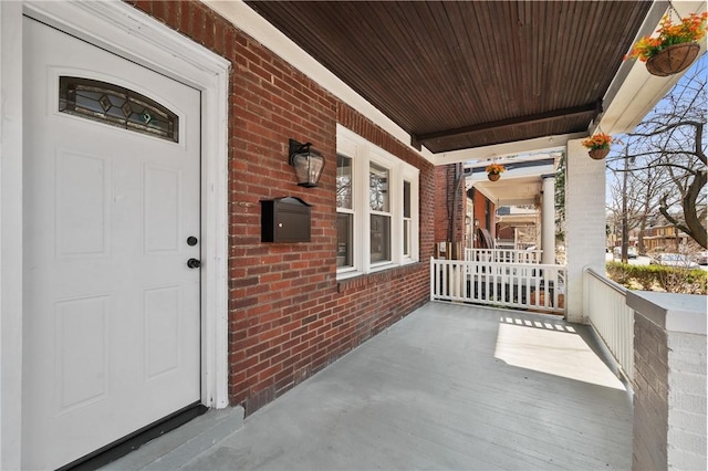 entrance to property with a porch and brick siding