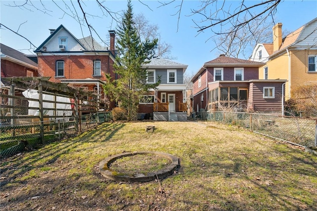 back of property featuring fence private yard, brick siding, a sunroom, and a lawn