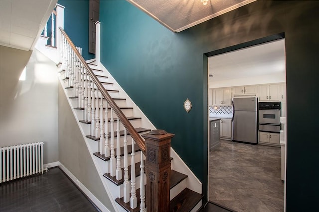 stairway featuring radiator heating unit and crown molding