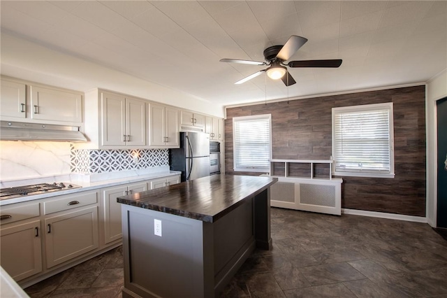 kitchen with appliances with stainless steel finishes, backsplash, a kitchen island, and ceiling fan