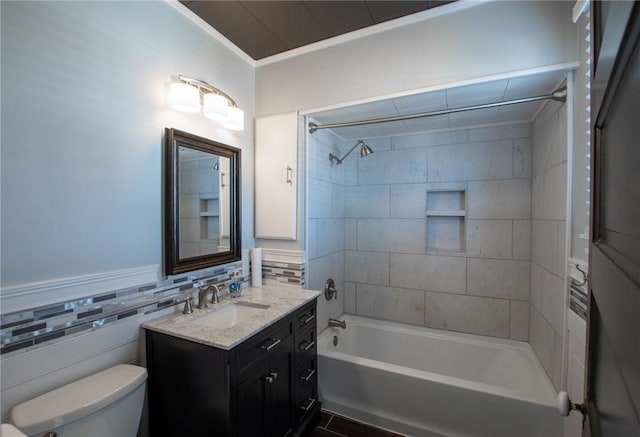 full bathroom featuring tiled shower / bath combo, toilet, vanity, tile walls, and ornamental molding