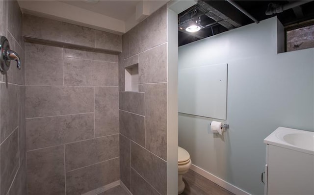 bathroom featuring a tile shower, vanity, and toilet