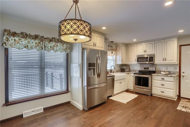 kitchen with decorative light fixtures, dark hardwood / wood-style flooring, sink, and stainless steel appliances