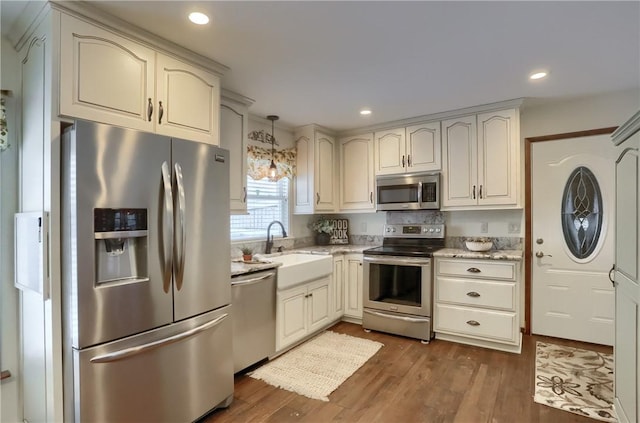 kitchen featuring pendant lighting, sink, dark hardwood / wood-style floors, light stone countertops, and stainless steel appliances