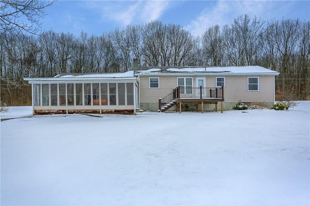 snow covered property with a sunroom and a deck