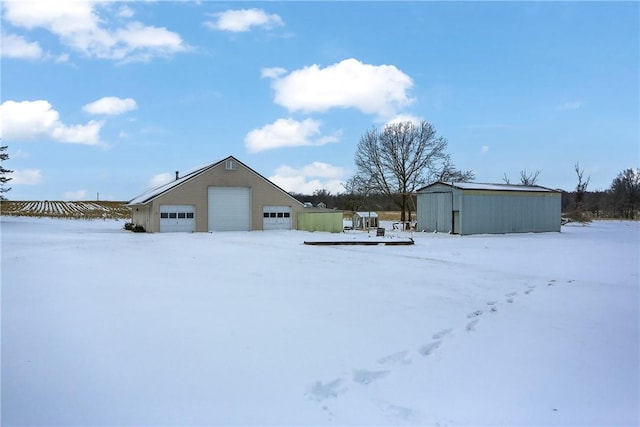 yard layered in snow featuring a garage and an outdoor structure