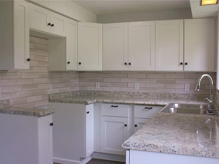 kitchen featuring white cabinets, decorative backsplash, and sink