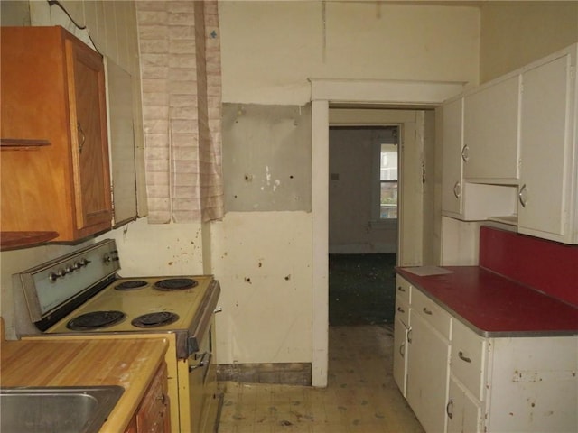 kitchen featuring white range with electric stovetop, white cabinetry, and sink