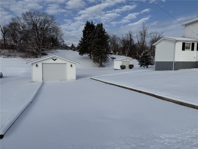 yard covered in snow featuring an outdoor structure and a garage