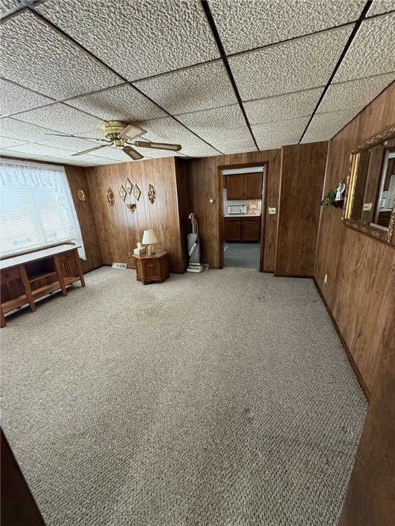 interior space with ceiling fan, carpet, and wood walls