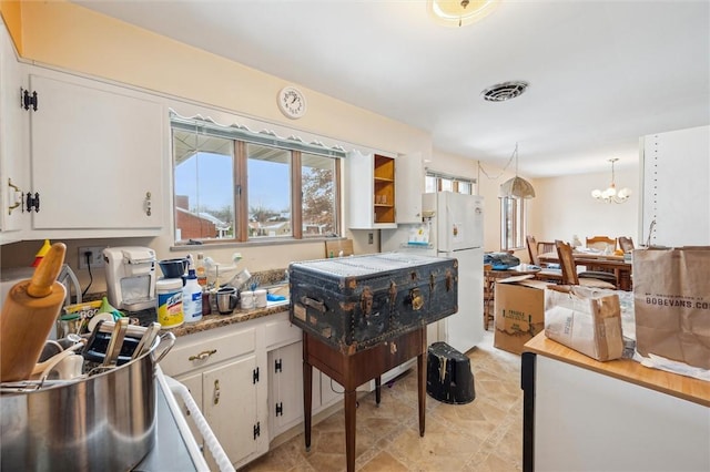 kitchen with white cabinets, decorative light fixtures, white fridge, and a notable chandelier