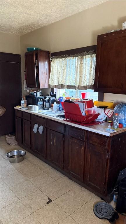 kitchen with dark brown cabinetry and a textured ceiling