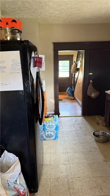 kitchen featuring black fridge and a textured ceiling