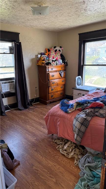 bedroom featuring wood-type flooring, a textured ceiling, and cooling unit